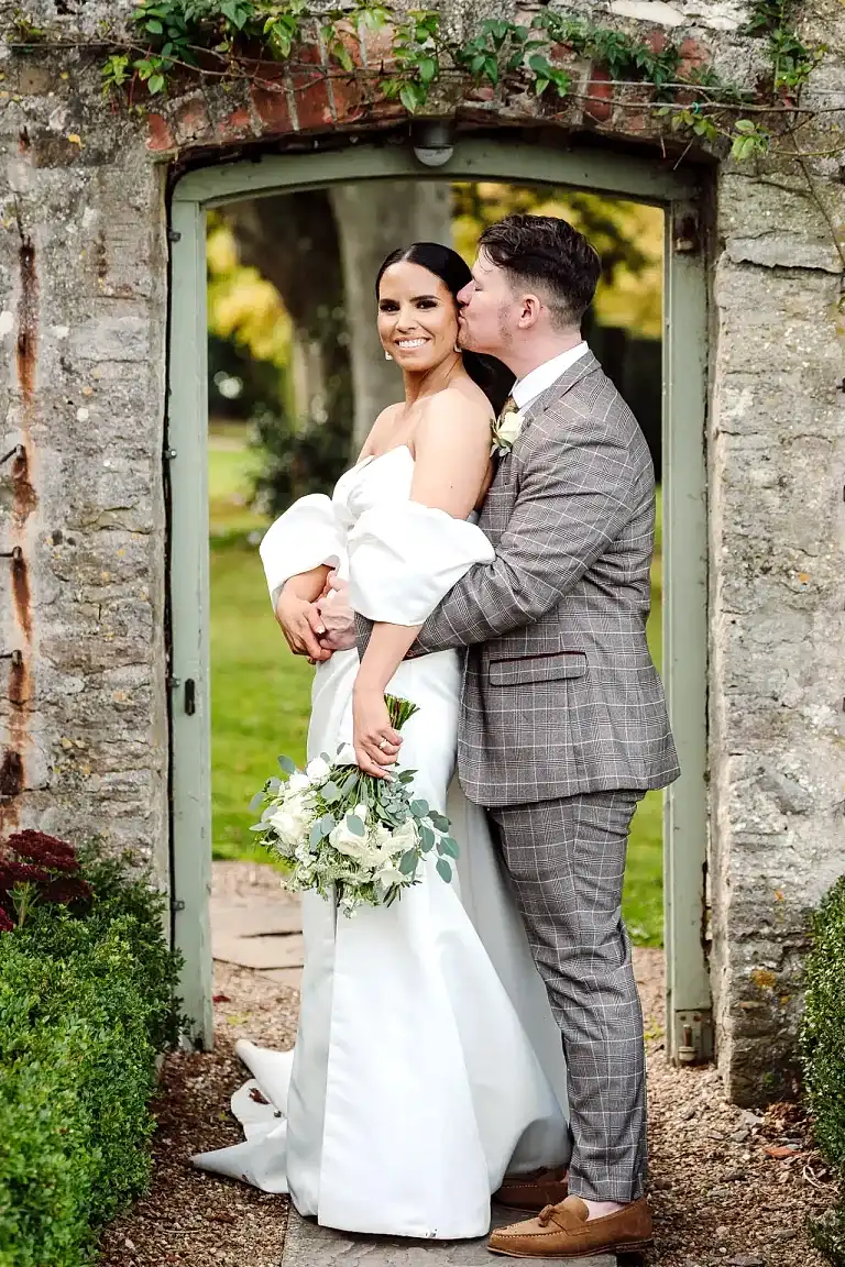 bride and groom pose in doorway of walled garden at coombe lodge wedding venue in somerset
