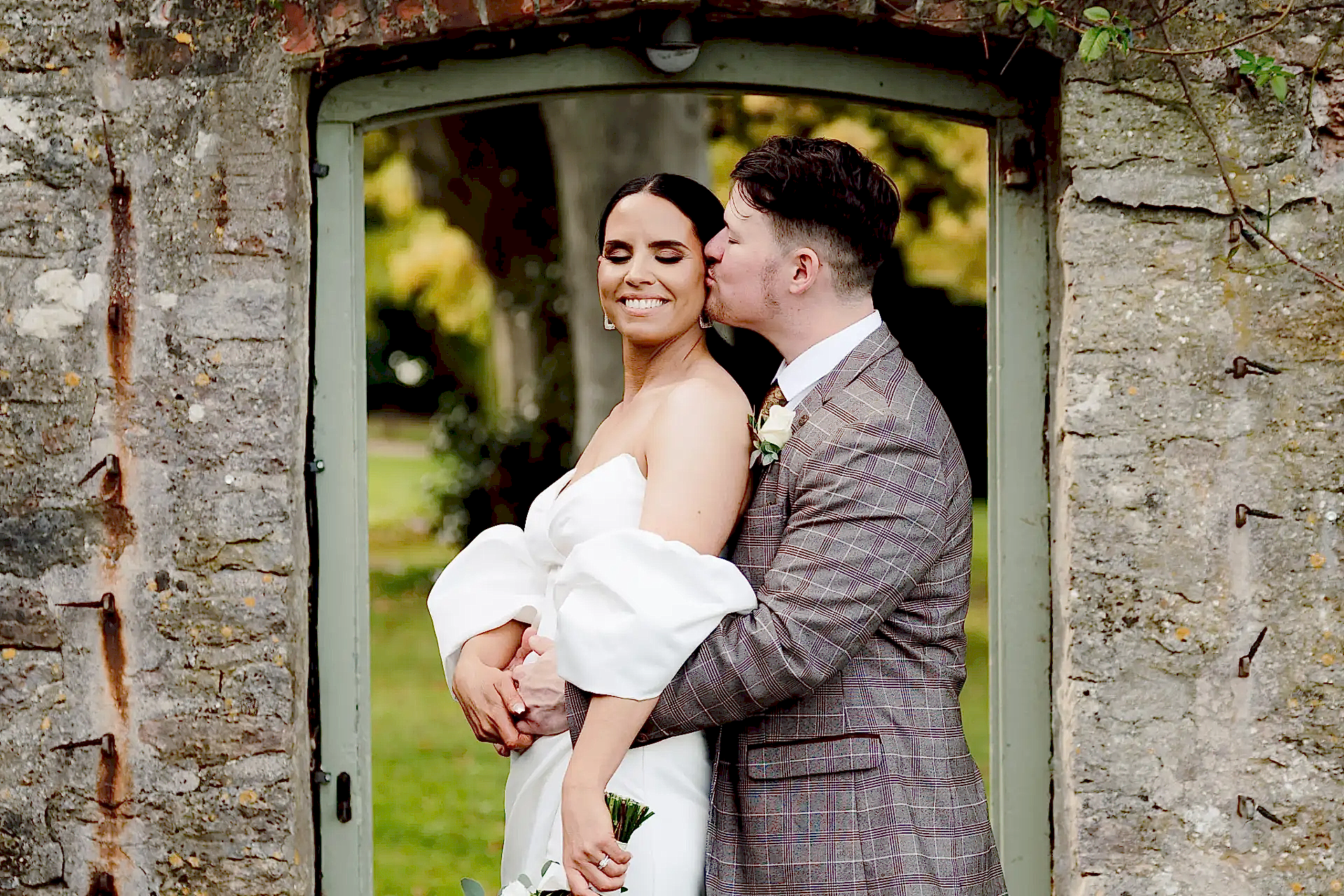 groom holds his bride under the walled garden doorway at coombe lodge in this reviews photo