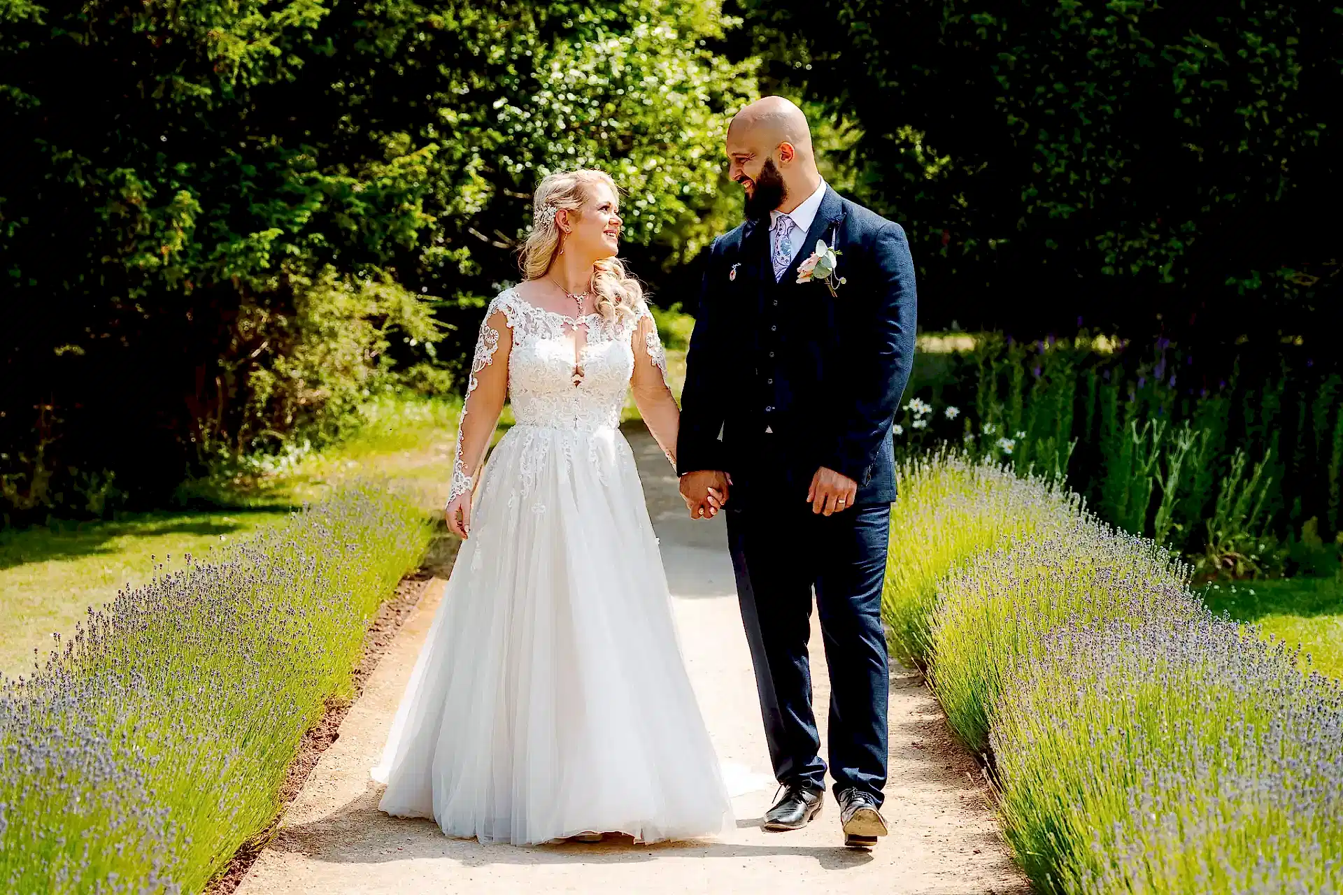 bride and groom hold hands walking through lavender at clevedon hall