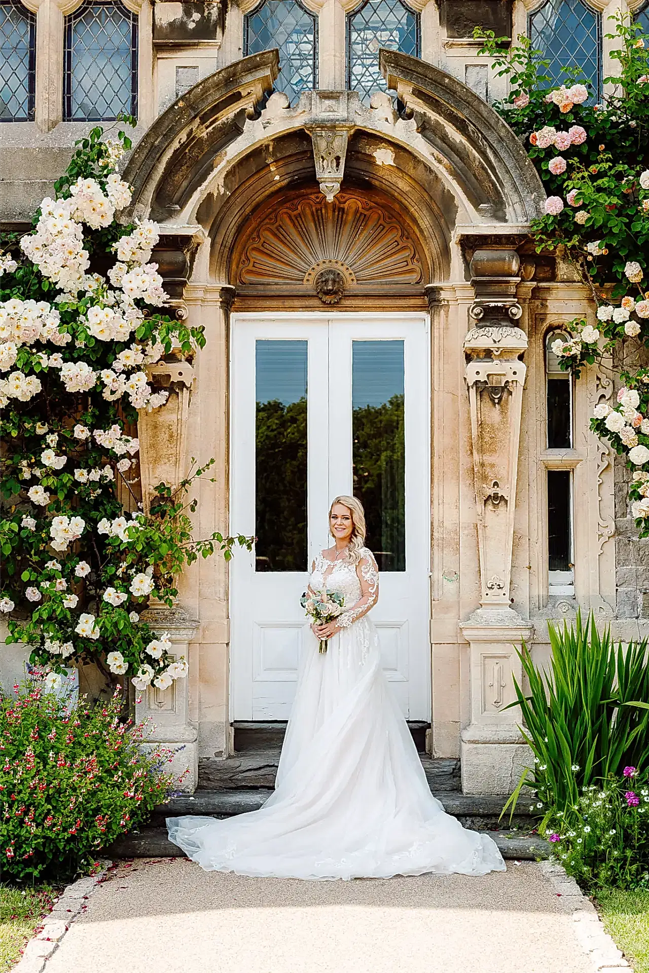 bride poses for wedding photographer in front of rose covered building