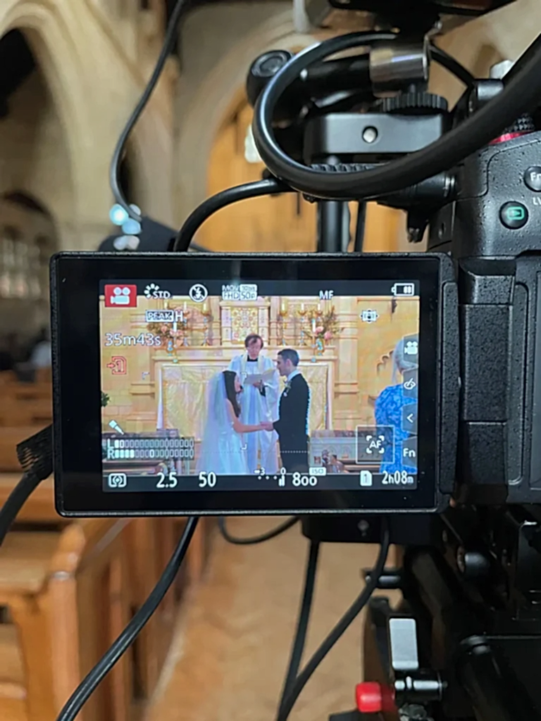 a view through the monitor screen of a camera recording a wedding live stream in a church