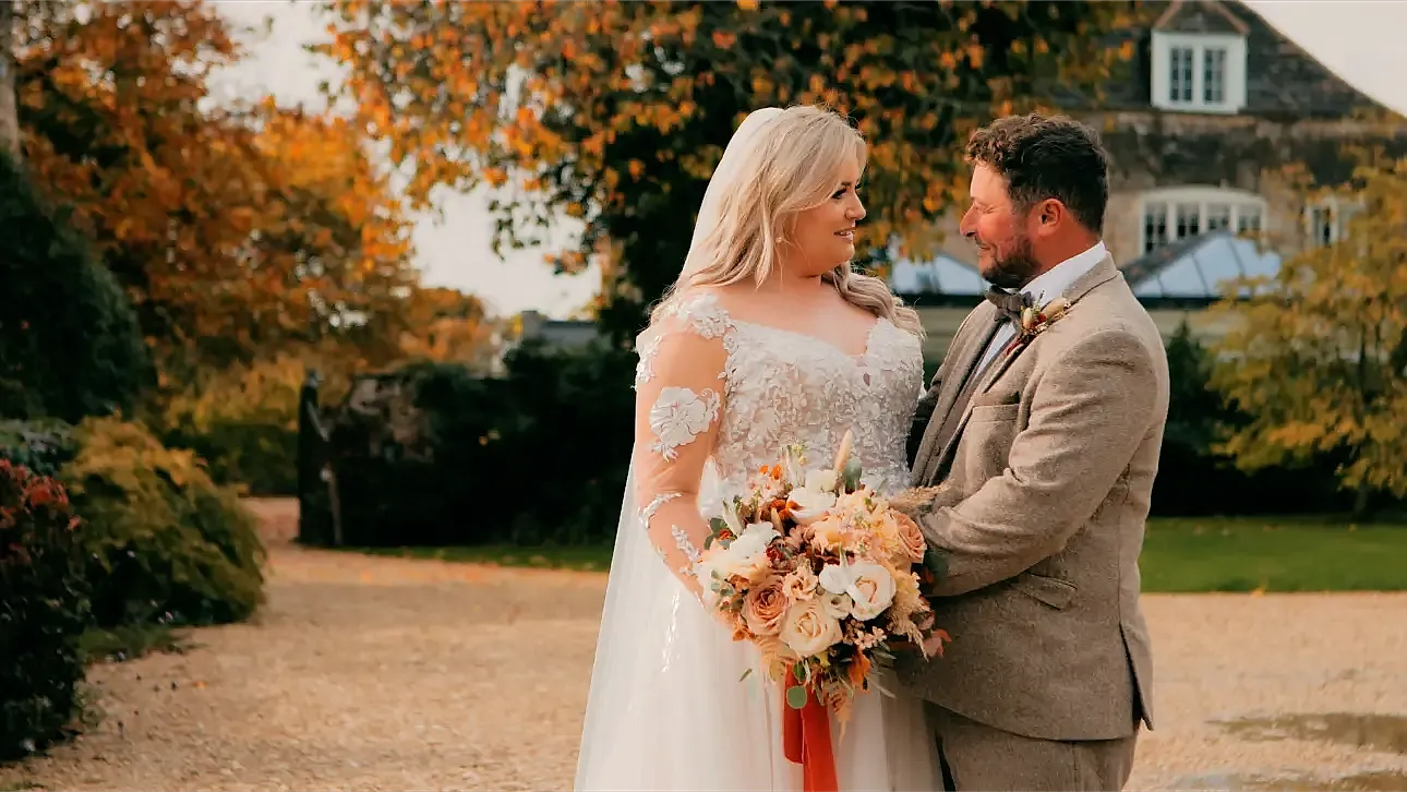 a man and woman in wedding attire posing for their wedding videographer at the Great Tythe Barn wedding venue in Tetbury