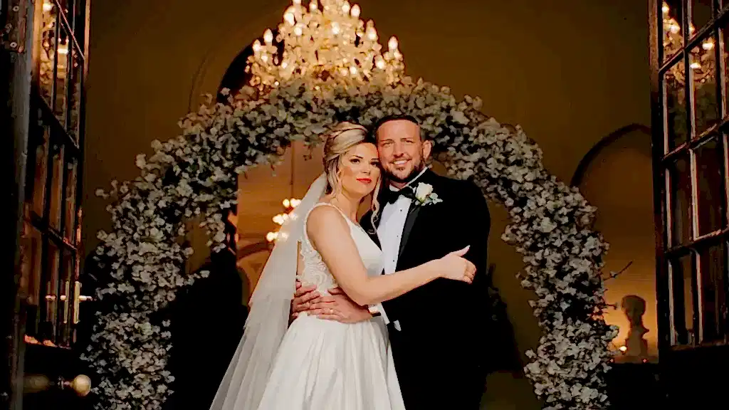 bride and groom embrace under a chandelier at Clearwell Castle