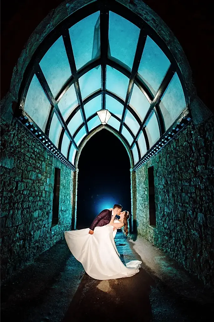 couple pose in a dramatic dip kiss at entrance to clearwell castle wedding venue