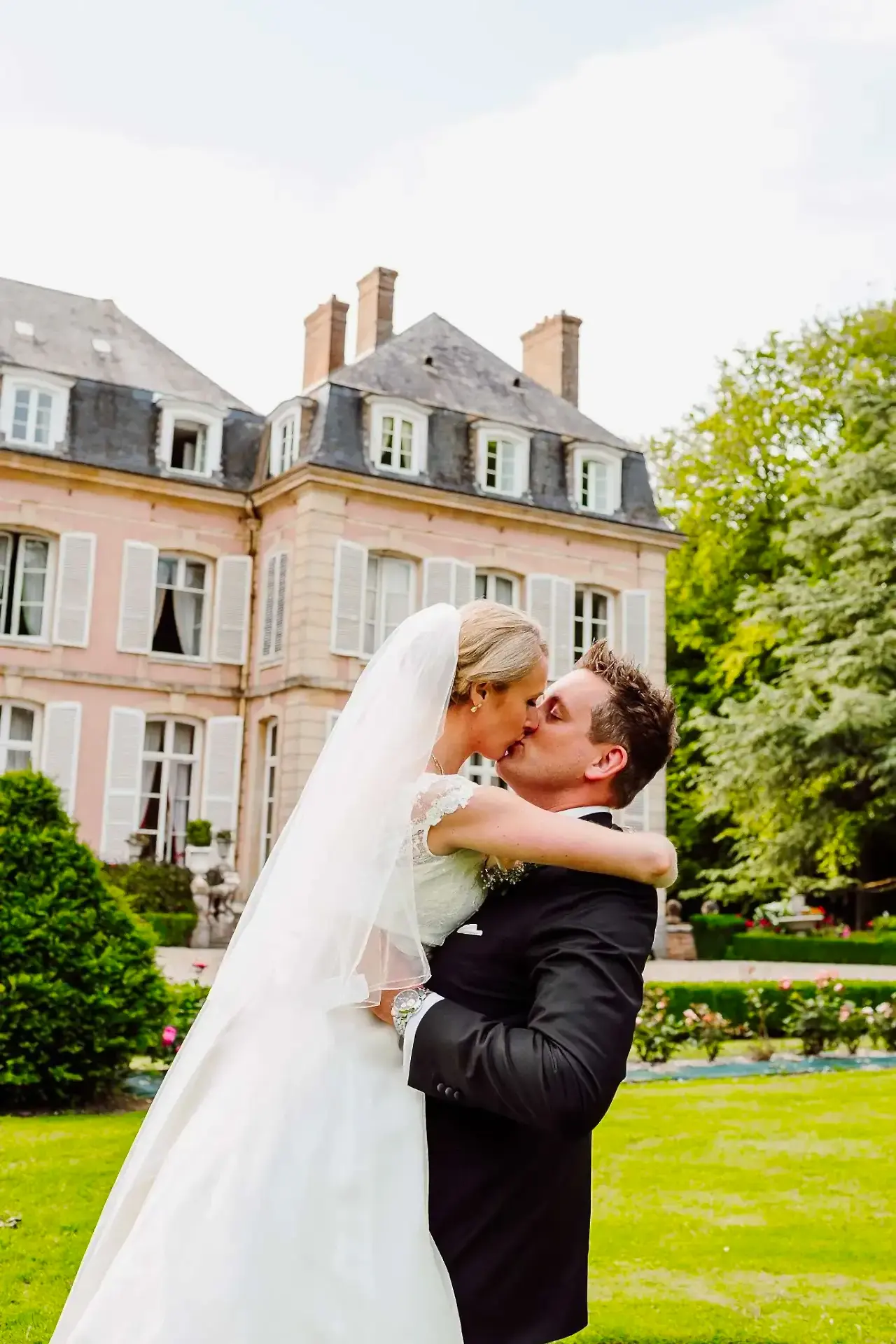 a man and woman kissing in front of a wedding venue in france