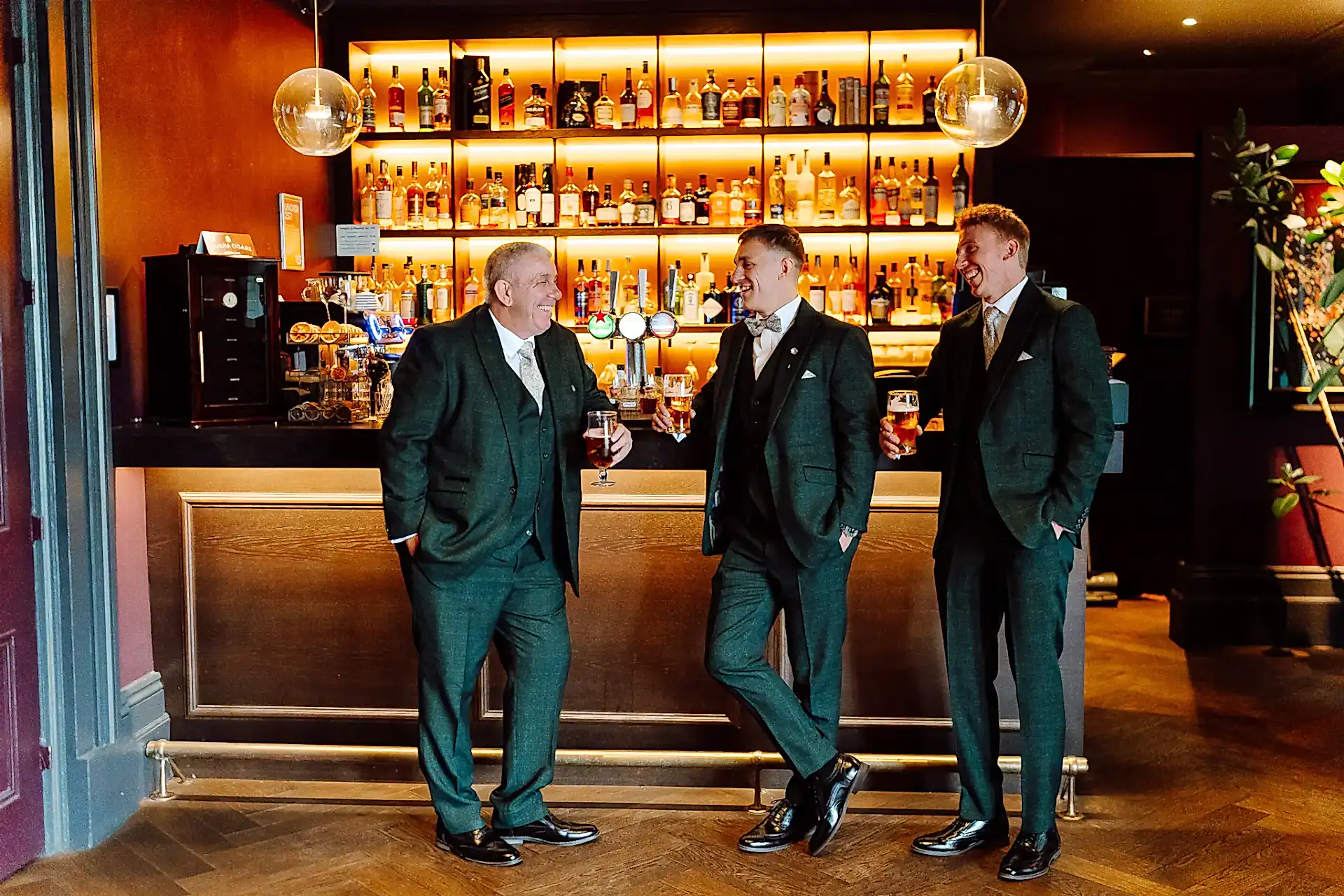 groom and his groomsmen stand up against the bar enjoying a wedding day drink inside the avon gorge hotel in bristol