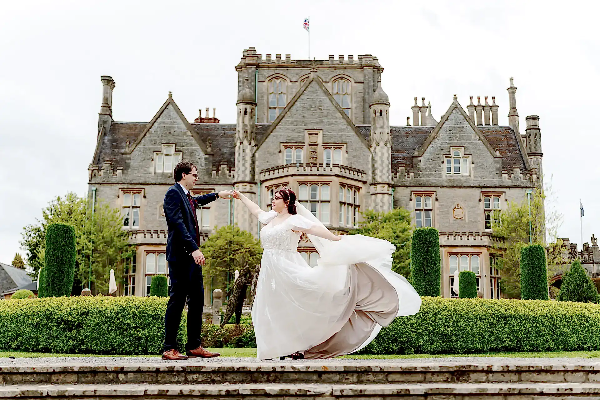 groom spins his bride in her wedding dress in front of Tortworth Court wedding venue