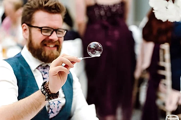 man balances bubble on the end of a bubble wand