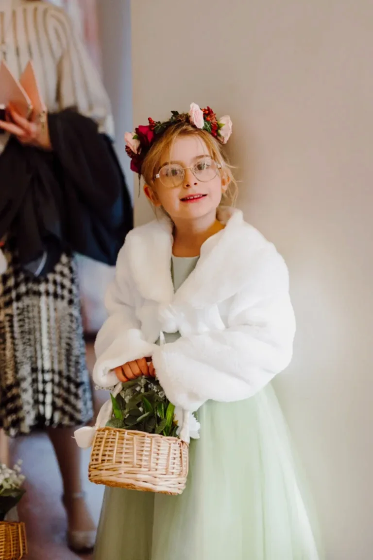 a flower girl in a white fleece shawl demonstrates some dress ideas for planning a winter wedding