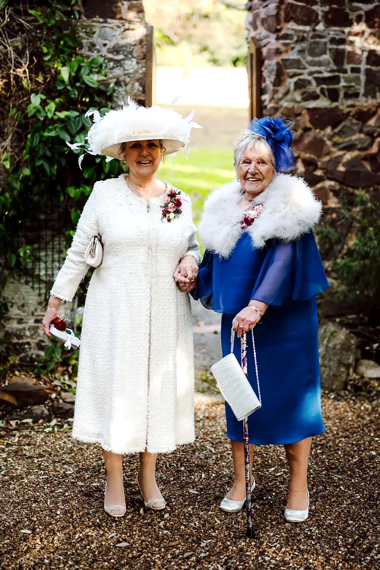 two women holding hands and walking in warm wedding dresses and hats