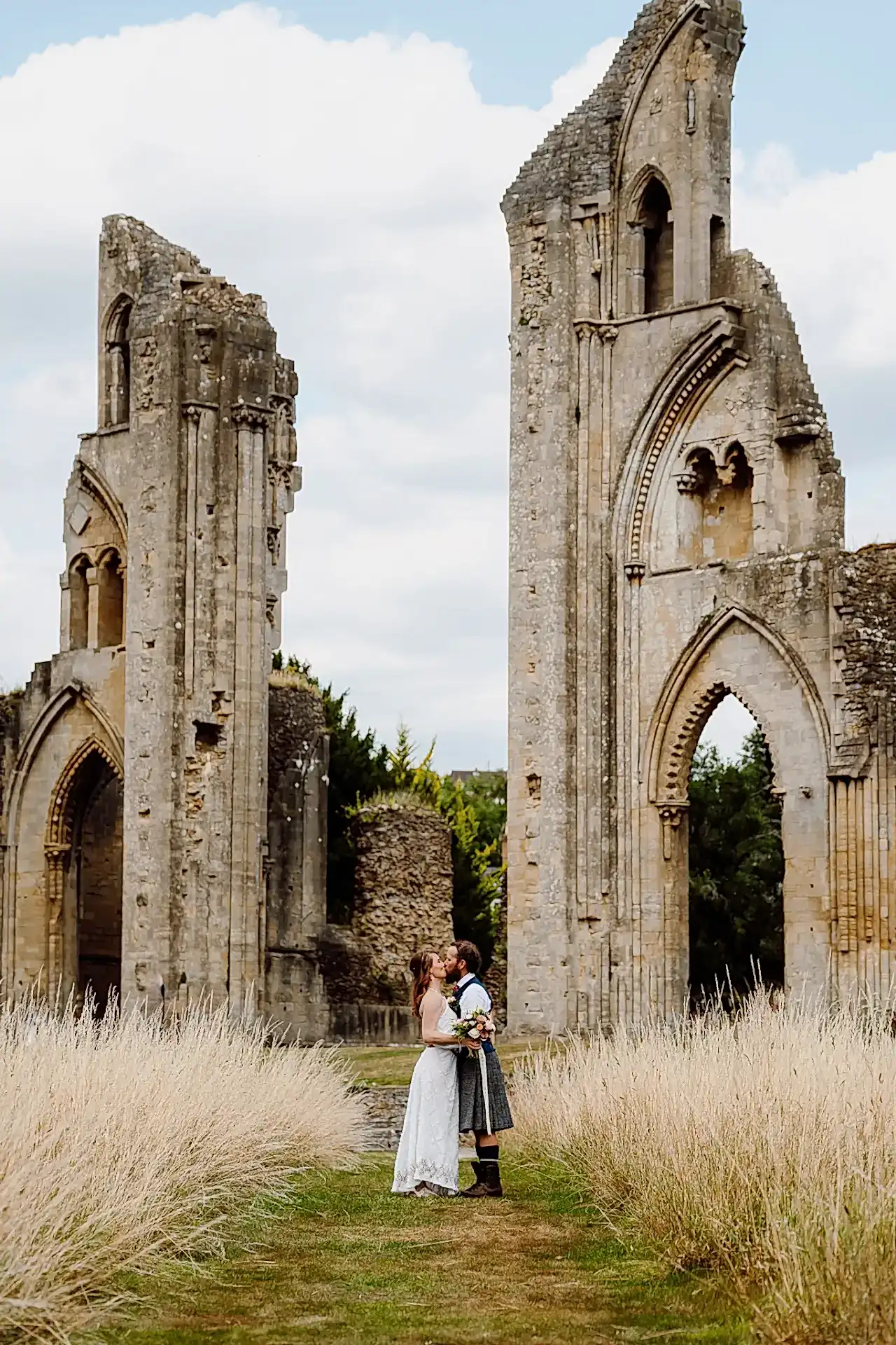 a man and woman kissing in front of an old stone ruins in glastonbury