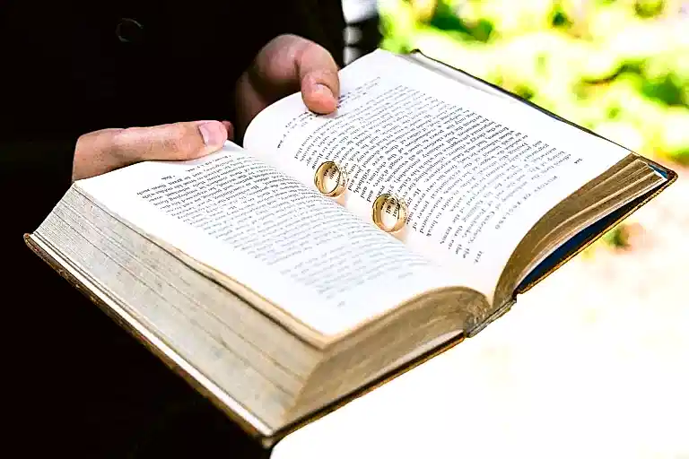 an open book holding two gold wedding rings in the page split