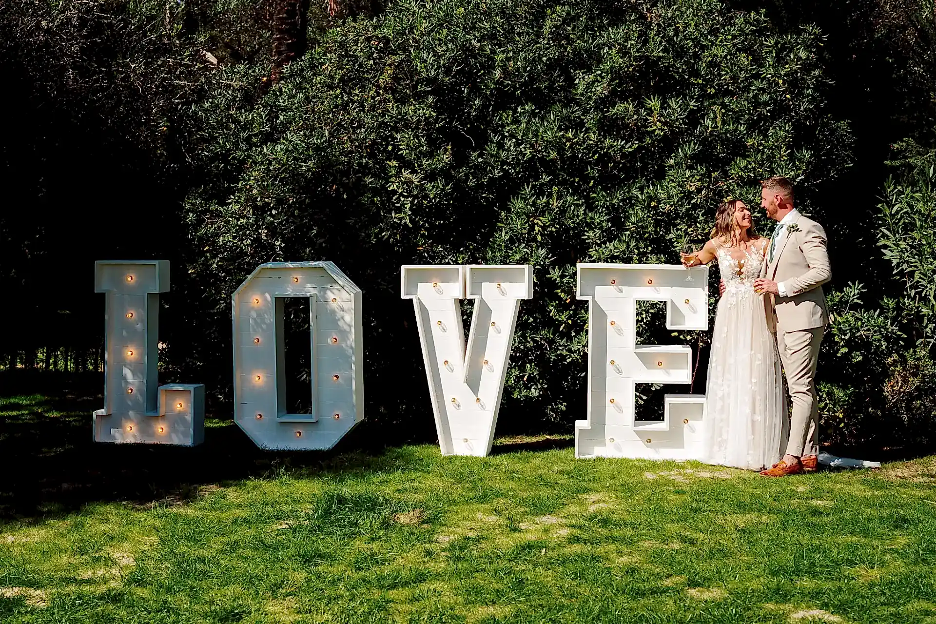 bride and groom stand by large love letters in the gardens at finca monasterio in spain