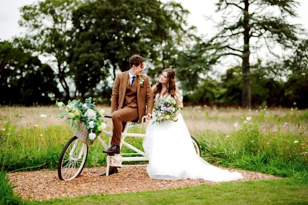 bride and groom sitting on a bicycle in the gardens of St Tewdrics House in Wales