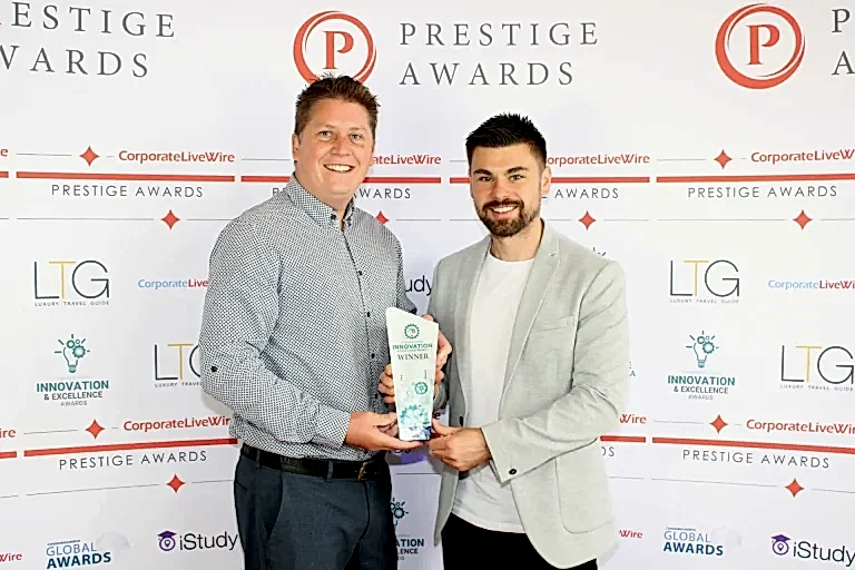 phil and sam from white villa hold the prestige awards trophy and pose for the camera as they accept this award for wedding videography company of the year