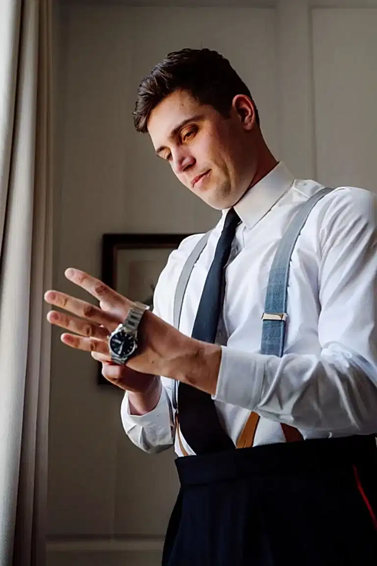 groom puts on his wristwatch as captured by his wiltshire wedding videographer