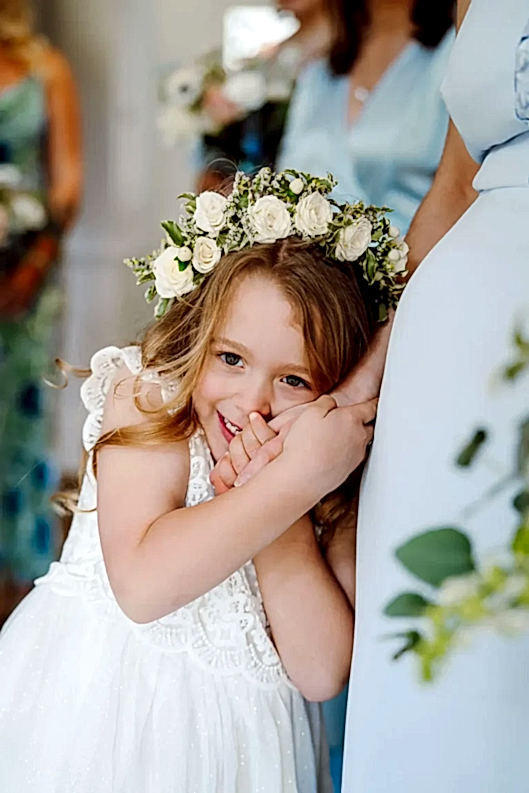 little flower girl cuddles her mums hand as she is candidly captured by her wiltshre wedding videographer