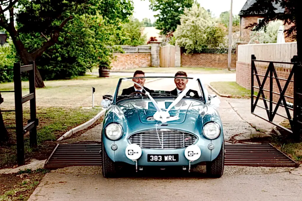 SNO0723-LOWRES-0137 groom and best man drive forwards in a vintage austin healey car