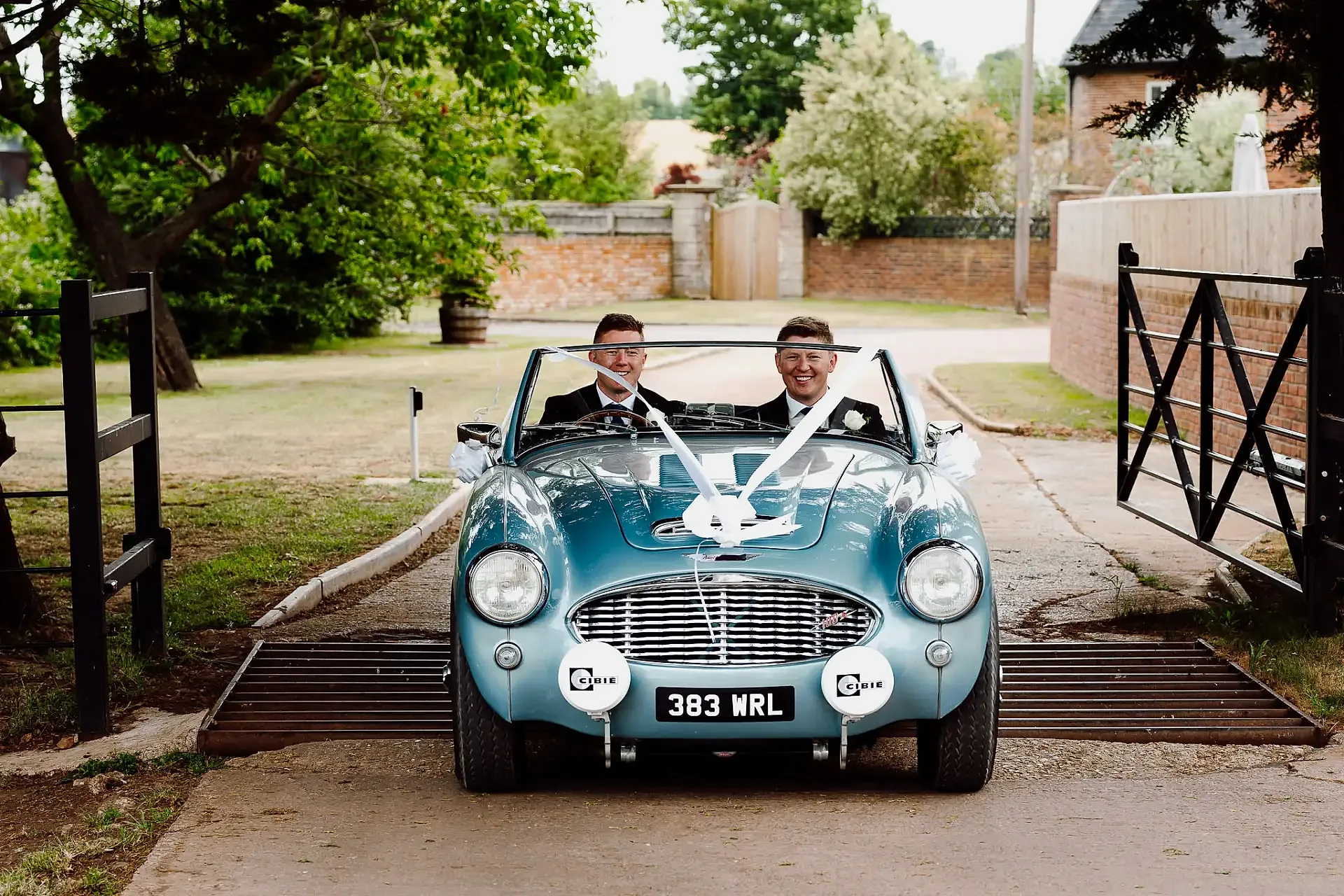 groom and best man drive forwards in a vintage austin healey car