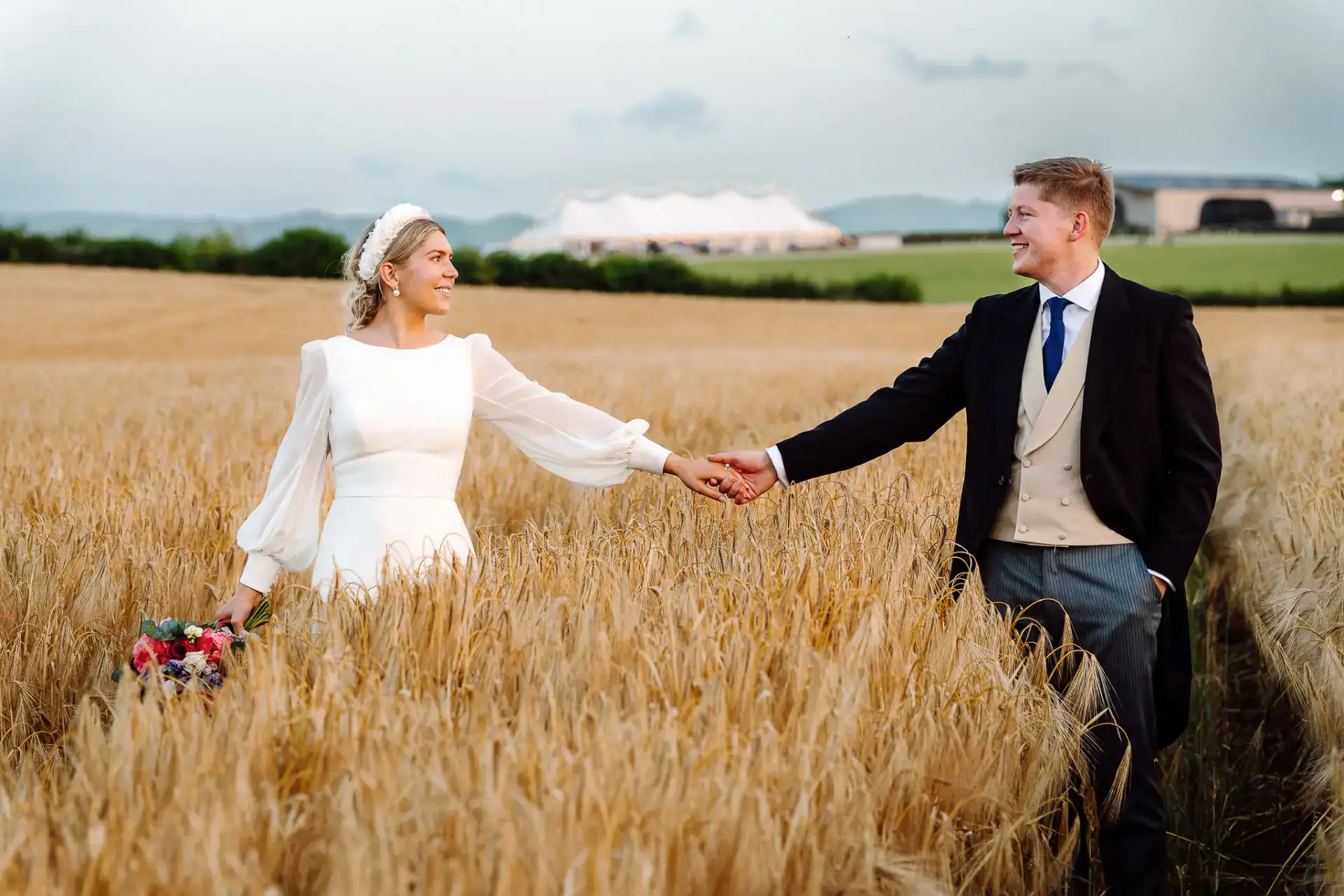bride and groom holding hands in a wheat field at sunset on a somerset wedding day