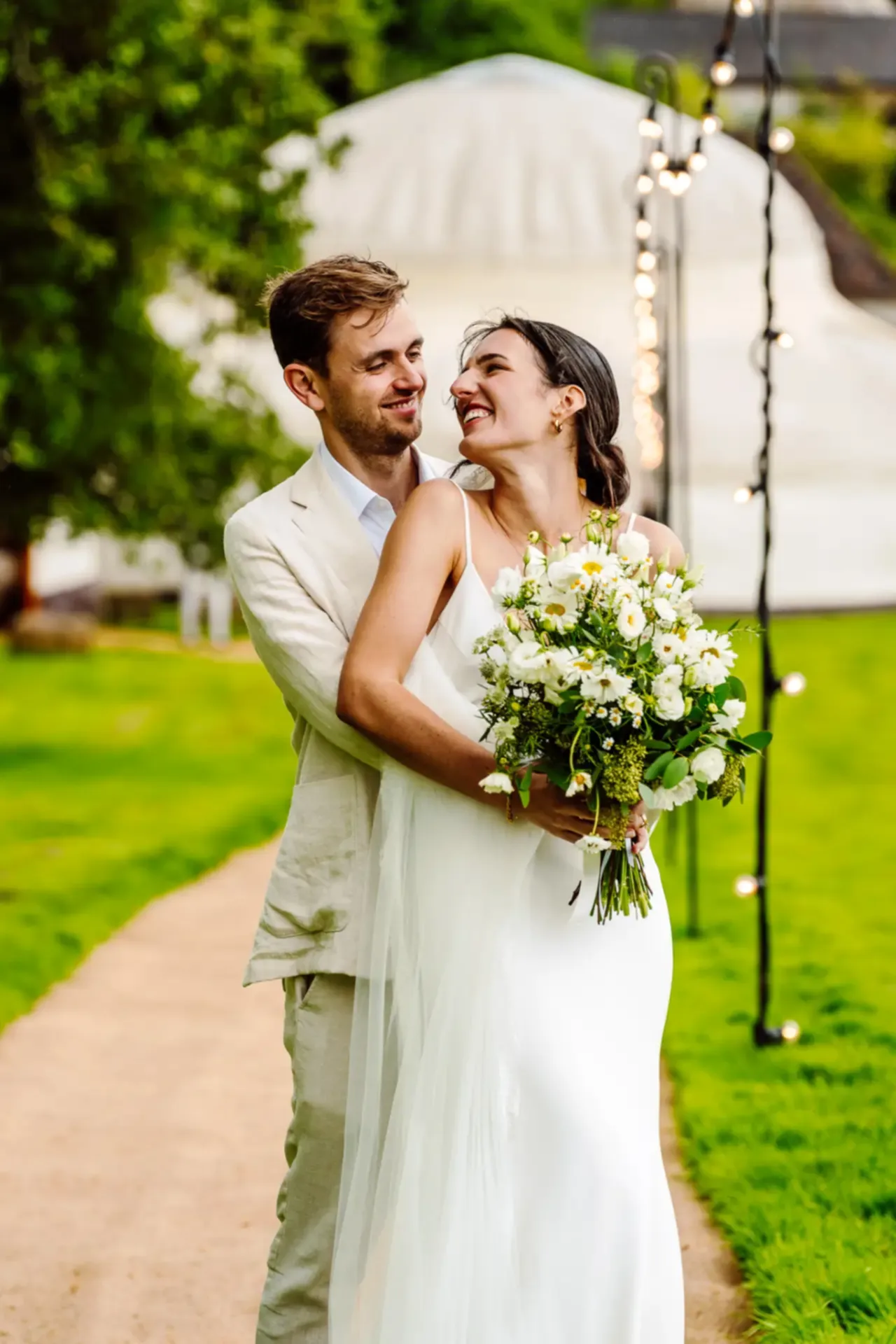 a man and woman holding flowers at Hilles House wedding venue as they pose for their cotswold wedding videographer
