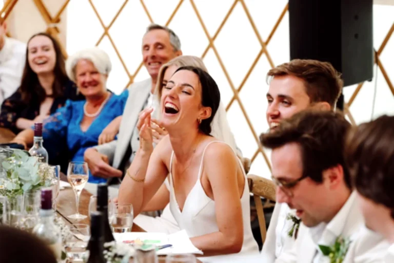 a woman laughing at a table with people in the background