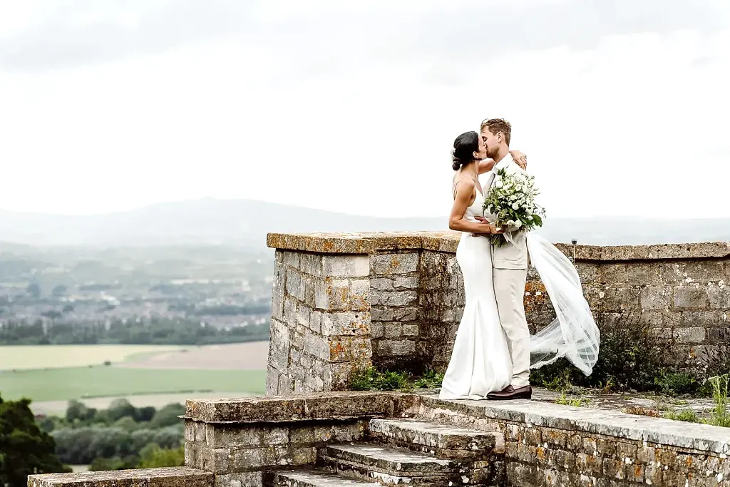 WAR0823-LOWRES-1005 bride and groom kiss at with the view of the cotswolds landscape behind them on their wedding day
