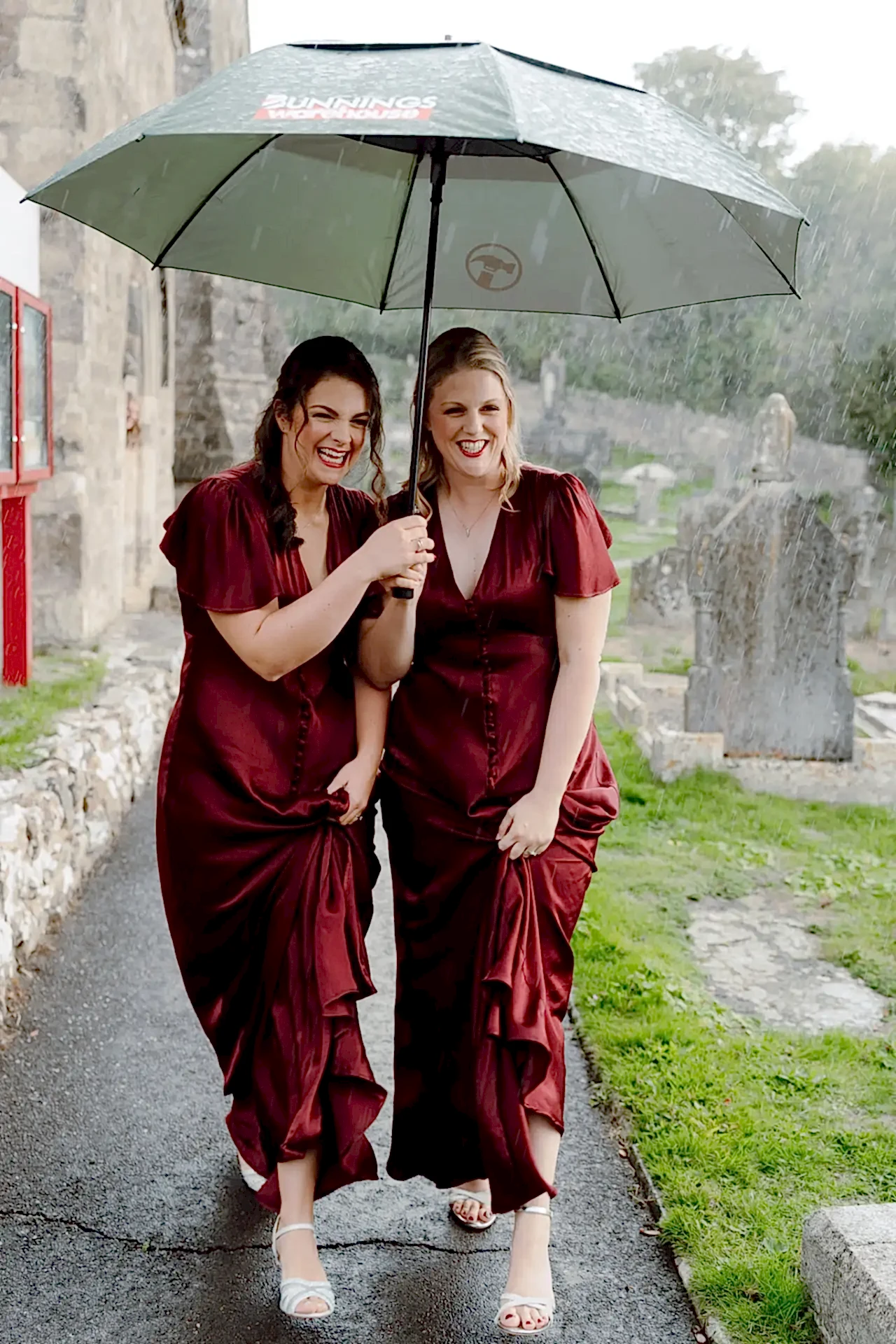 two bridesmaids work out how to plan around rain on your wedding day by carrying an umbrella in the rain