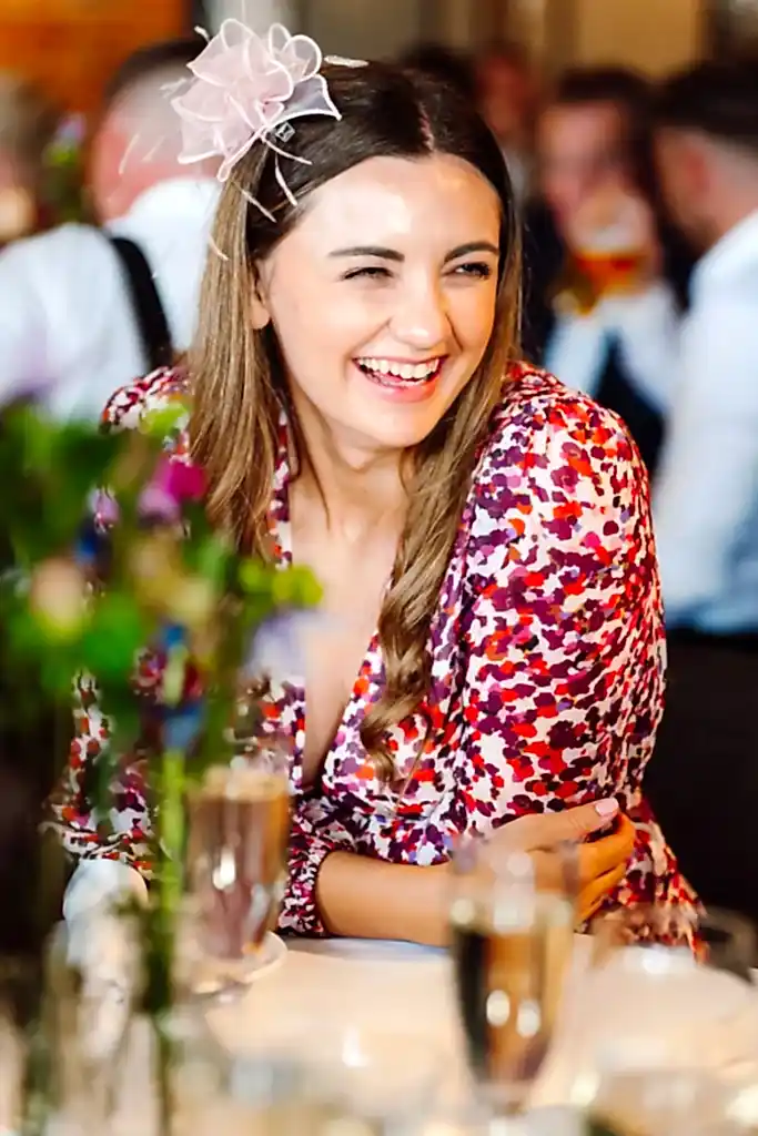 a woman smiling at the camera while sat at a wedding table at the avon gorge hotel